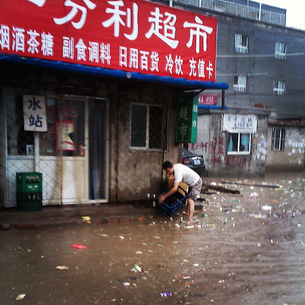 2013/07/15 — 小超市老板正在捞被雨水冲走的啤酒瓶，(我在东沙，晓梅)
