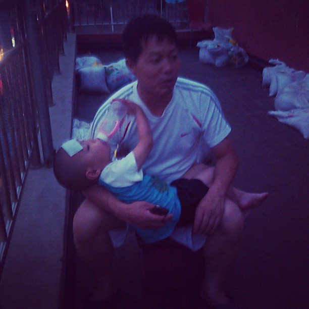 2013/07/20 — 这是我们邻居的孩子发烧了，他爸爸抱着他额头上还贴着退烧贴呢（文琼2013年7月18晚上在东三旗我们出租房的三楼阳台）