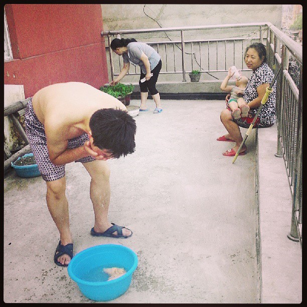 2013/08/10 — 早上在阳台上的三个人，洗脸的，弄鱼香菜的，抱孩子的（文琼拍）